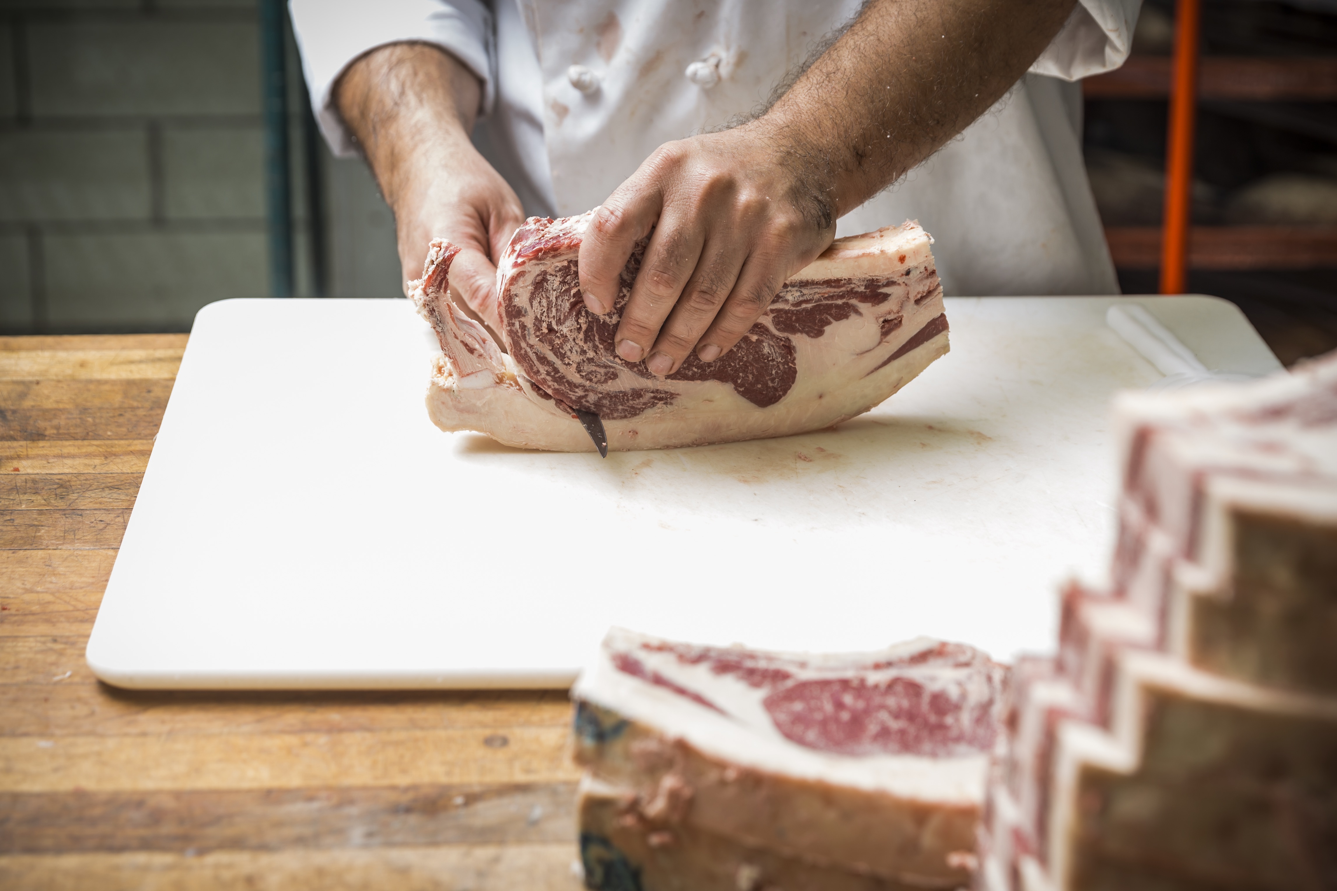 The Roadhouse butcher trims a freshly cut ribeye steak.
