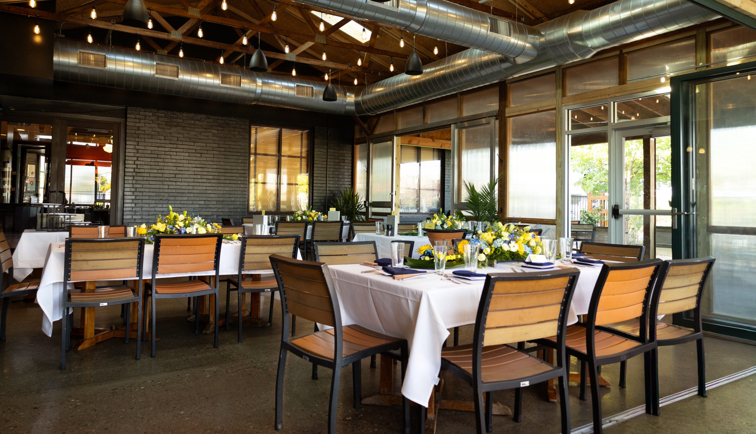 A view of a patio dining space with tables set with white linens and flowers