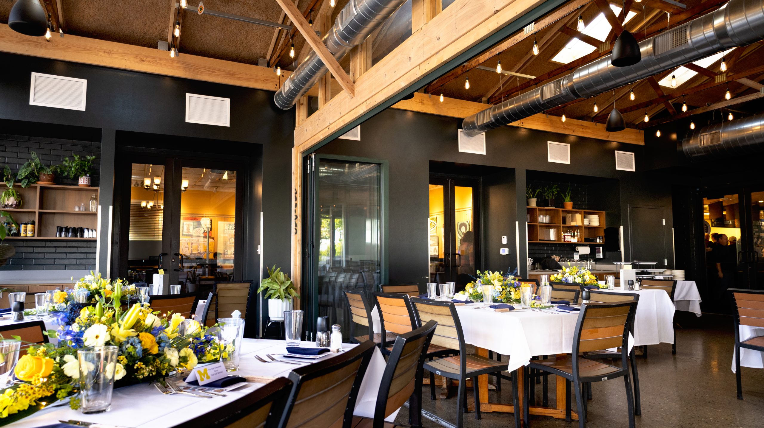 A view of a patio dining space with tables set with white linens and flowers