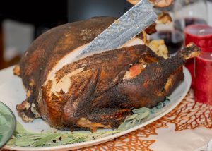 A large coffee spiced rubbed turkey with a chef's knife carving into it.