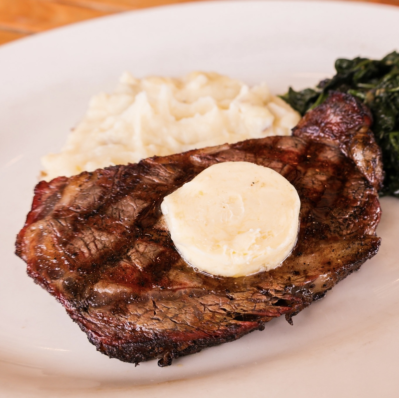 A grilled ribeye steak topped with butter.