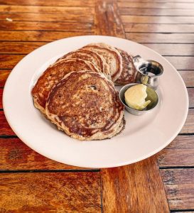 A plate of golden-brown pancakes with butter and syrup.