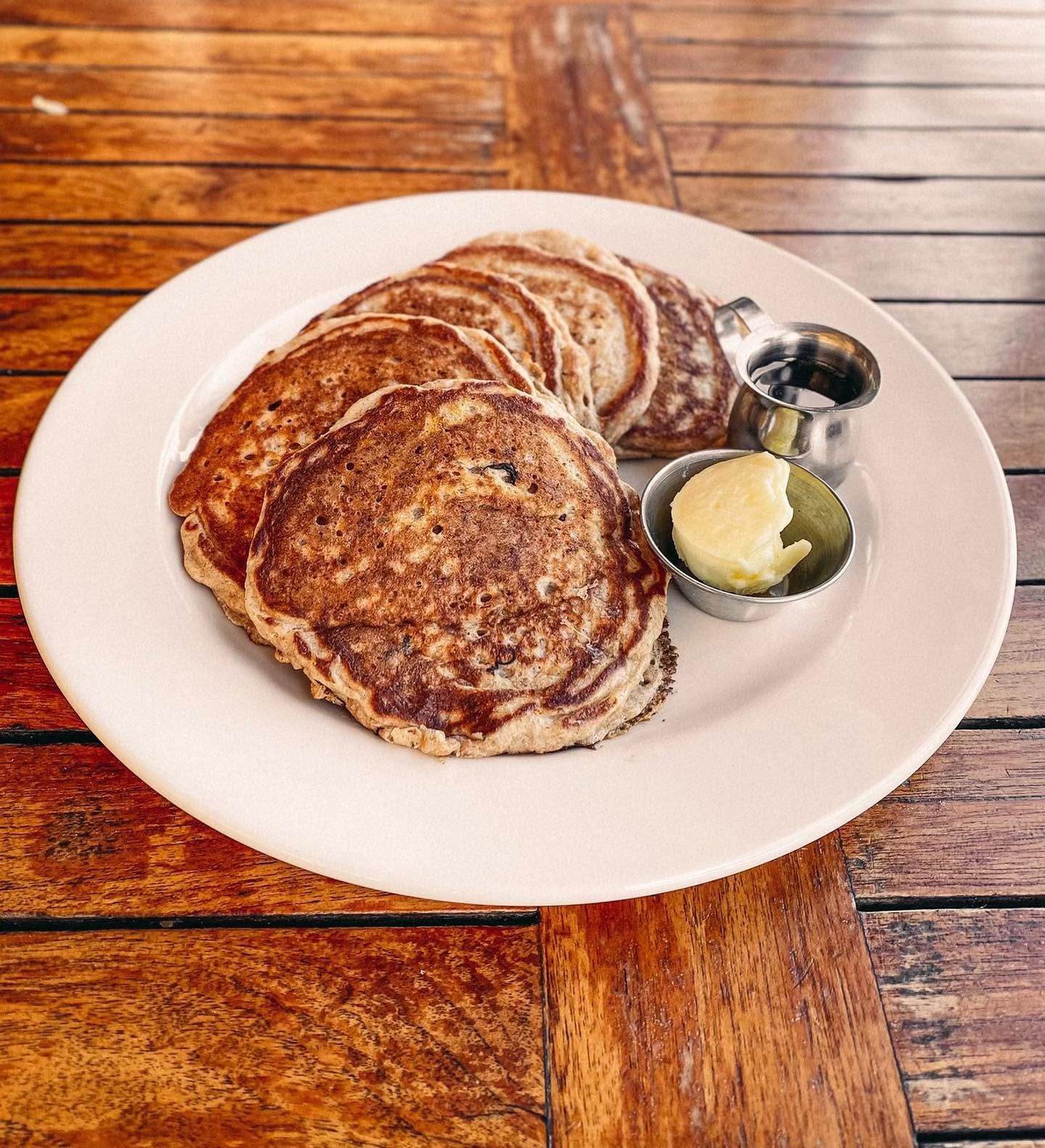 A plate of golden-brown pancakes with butter and syrup.