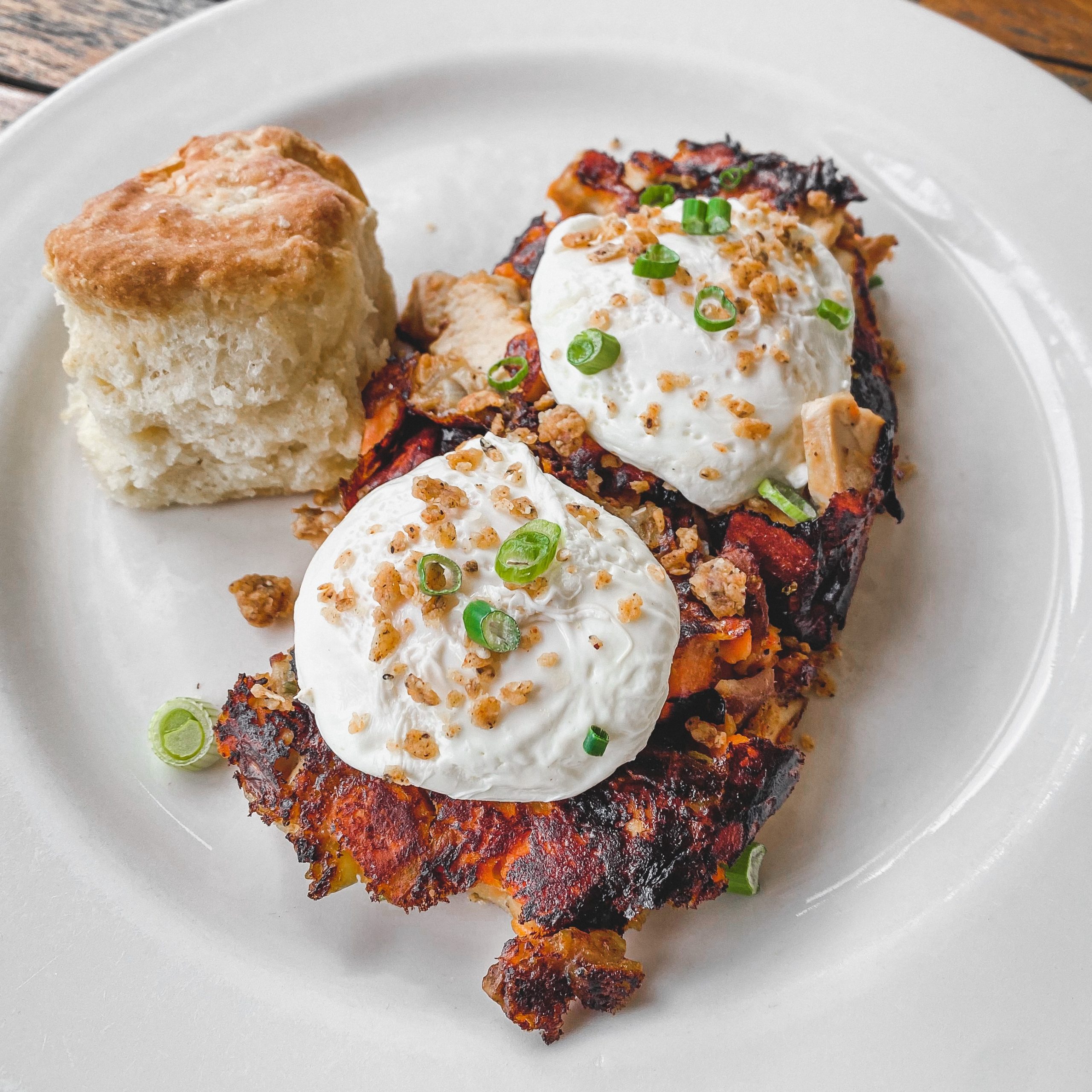 A plate of sweet potato hash topped with fried chicken pieces and two poached eggs.