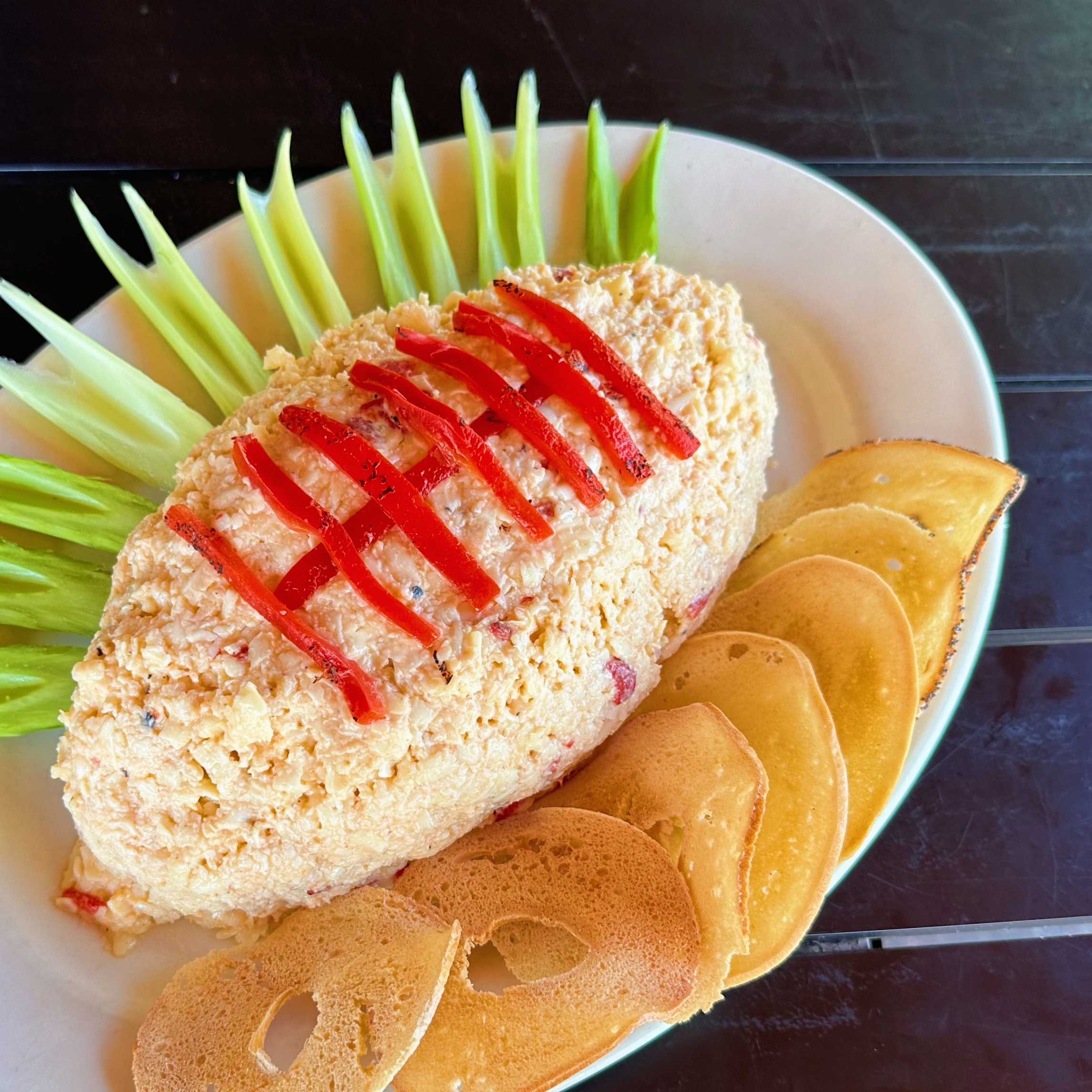 A pimento cheese football with celery sticks and bagel chips.